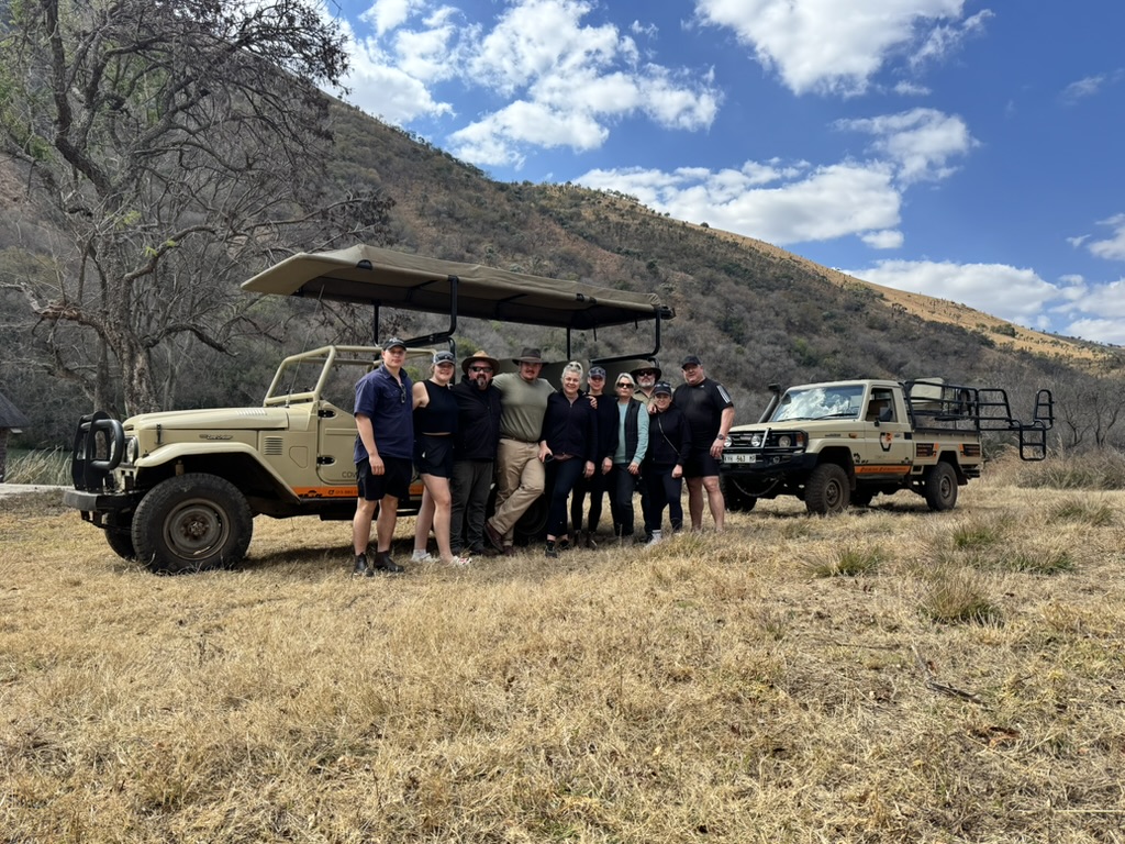 Cowley Safaris guests standing with two safari vehicles